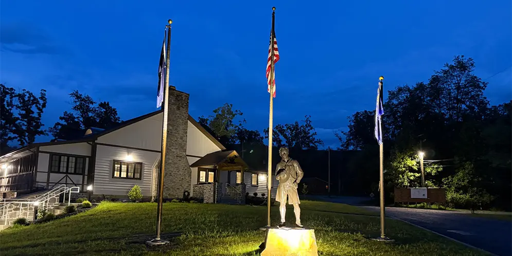 Tuckahoe Service Center at dusk, with illuminated building and flagpoles.